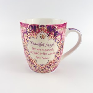 Pode incluir: Uma caneca de cerâmica com interior branco e um padrão decorativo rosa, roxo e dourado. A caneca apresenta o texto "Beautiful Angel, you are a sparkle of light in the world" em uma moldura decorativa.