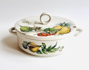 Peut inclure: Un plat à casserole en céramique blanche avec un couvercle, orné d'illustrations colorées de fruits et légumes. Le couvercle est doté d'une poignée en anneau. Le plat a deux poignées latérales.