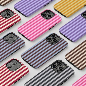May include: A collection of colorful phone cases with a striped pattern. The cases are in various colors, including pink, purple, blue, and yellow. The cases are arranged in a grid pattern, showcasing the different designs.