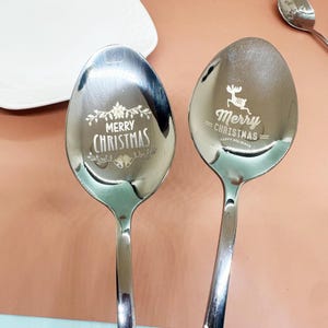 以下が含まれることがあります： クリスマスのお祝いの言葉が刻まれたステンレス製のスプーン2本。1本は「Merry Christmas」と花とベルの装飾。もう1本はトナカイと「Merry Christmas Happy Holidays」の文字が特徴です。