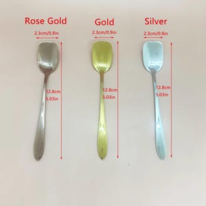 May include: Three spoons in rose gold, gold, and silver. Each spoon has a rectangular head, measuring 0.9 inches wide, and a slender handle. The spoons are 5.03 inches long. The text "Rose Gold", "Gold", and "Silver" is above each spoon.