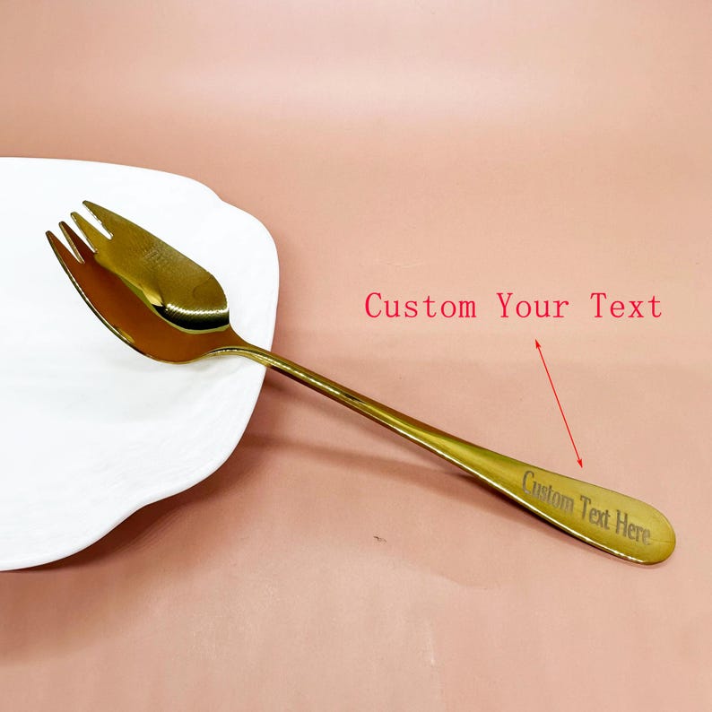 May include: A gold-coloured serving fork with a three-pronged head and a long handle. The handle has the text "Custom Text Here" engraved on it. The words "Custom Your Text" are written in red above the fork.