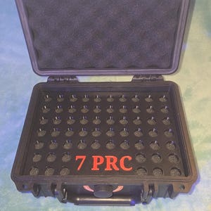 May include: Black, open, hard-shell case with a foam interior and a grid of small holes. The text "7 PRC" is printed in red on the case. The case is designed to hold small cylindrical objects.