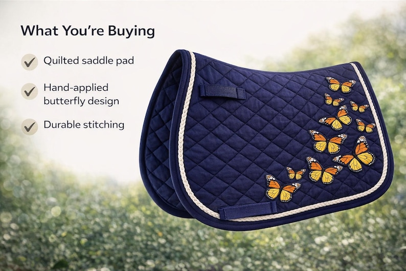 May include: A navy blue quilted saddle pad with a white trim and hand-applied butterfly design. The butterflies are orange and yellow. The saddle pad has durable stitching.