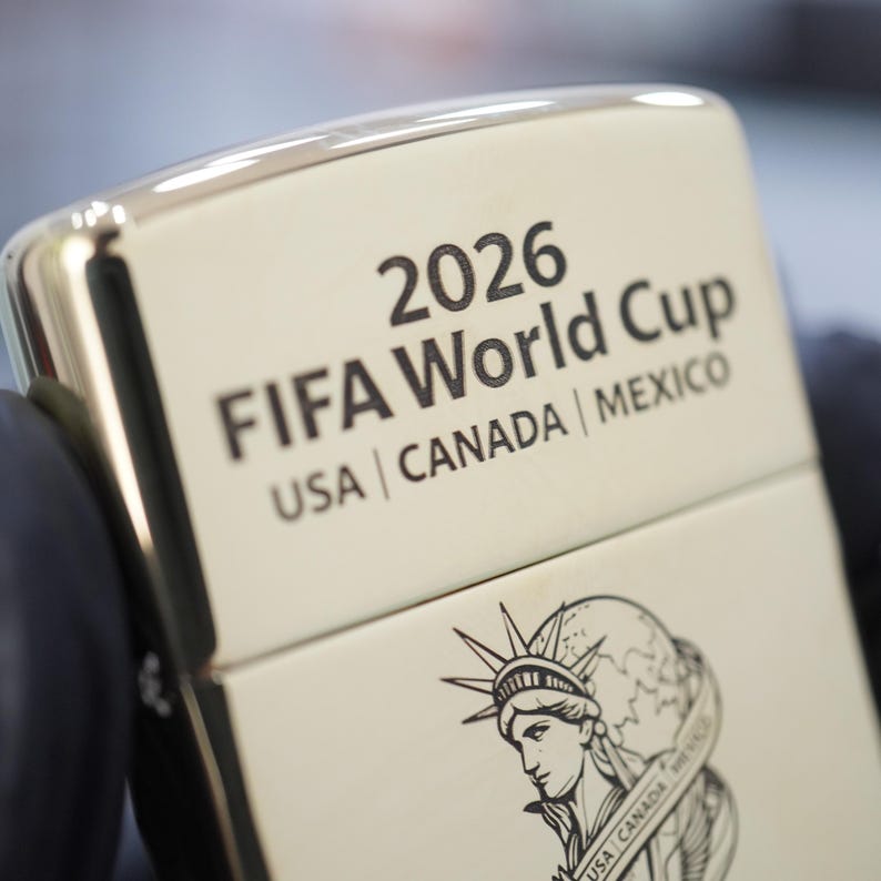 以下が含まれることがあります： 2026 FIFA World Cup USA | CANADA | MEXICOという刻印と、地球儀を持ち国名が書かれた帯を纏った自由の女神のグラフィックイラストが施された、銀色の金属製ライター。