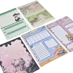Op de afbeelding: Een verzameling Sailor Moon-thema briefpapier. De set bevat verschillende notitieblokken en plannerpagina's met kleurrijke illustraties van anime-personages, bloemmotieven en takenlijsten. Het kleurenpalet omvat roze, blauw, groen en wit.