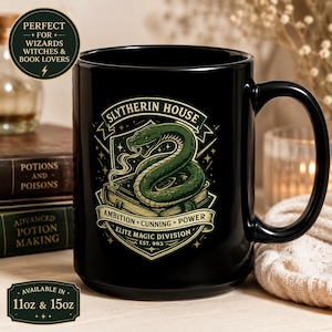 Puede incluir: Taza de cerámica negra con el escudo de la Casa Slytherin, una serpiente verde y estrellas. El texto incluye "Slytherin House", "Ambition, Cunning, Power" y "Elite Magic Division". Disponible en tamaños de 312 ml y 425 ml.