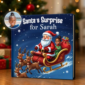 以下が含まれることがあります： 「Santa's Surprise for Sarah」というタイトルのパーソナライズされた子供向けの本。表紙には、トナカイに引かれたそりに乗ったサンタクロースと若い女の子のイラストが描かれています。女の子の小さな写真が左上にあります。