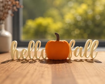 May include: A decorative sign featuring the white cursive text hello fall with an orange pumpkin replacing the letter o. The pumpkin has a brown stem and a smooth surface. The sign is constructed as a single piece with a flat base.