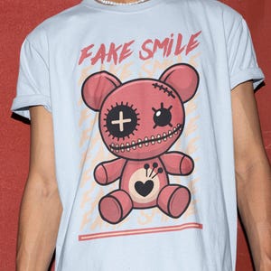 Koszulka z grafiką "Fałszywy uśmiech" z różowym misiem | Urocza, ciemna, estetyczna pluszowa lalka w stylu streetwear | Emo-gotycki prezent dla obu płci