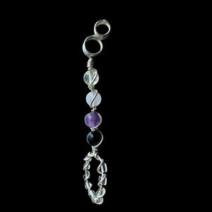 May include: A silver-toned wire-wrapped pendant featuring a series of colorful gemstones. The pendant includes clear, white, purple, and black beads, with a loop at the top and a decorative loop at the bottom. The background is solid black.