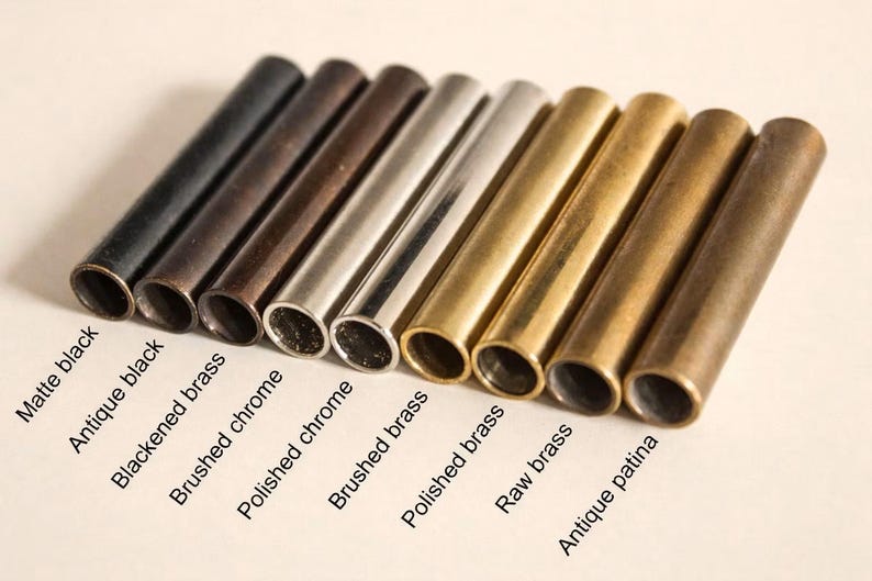 May include: An assortment of cylindrical metal tubes in various finishes, including matte black, antique black, and brushed chrome. The tubes are labeled with their respective finishes, such as "Raw brass" and "Antique patina".