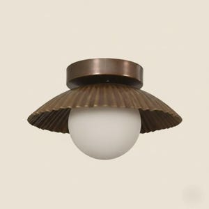 May include: A brass-colored ceiling light fixture with a scalloped shade and a round, white globe. The fixture has a circular base and a warm, metallic finish. The design is reminiscent of a seashell.