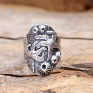 May include: A silver ring with a detailed design of starfish and sea urchins. The ring is made of sterling silver and has a textured finish.