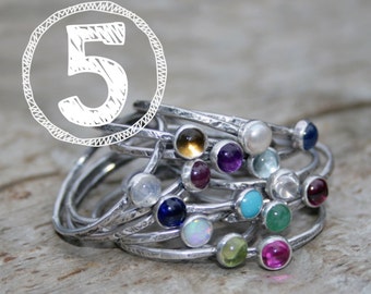 May include: A set of five silver rings with colorful gemstones. Each ring features a different gemstone, including amethyst, turquoise, opal, and more.