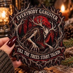 May include: A circular embroidered patch featuring a skeletal deer-like creature with large antlers in a dark forest. The text "EVERYBODY GANGSTER" is arched at the top and "TILL THE TREES START TALKIN" is at the bottom in a cream-colored font.