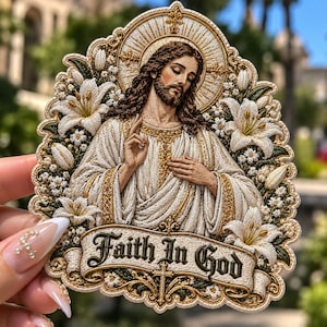 May include: An embroidered patch featuring a depiction of Jesus with a halo, surrounded by white lilies and green foliage. Below the figure, a banner with gold trim and dark lettering reads Faith In God, accented by a small cross.