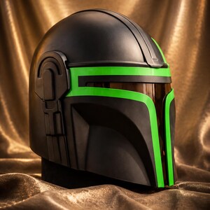 May include: A matte black helmet featuring a T-shaped visor opening accented with vibrant neon green trim. The helmet includes a dark, semi-transparent brown face shield and a mechanical side detail on the right temple area of the headgear.