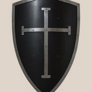 May include: A black shield with a silver cross design. The shield has a silver trim and is secured with rivets. The shield is a medieval-style design.