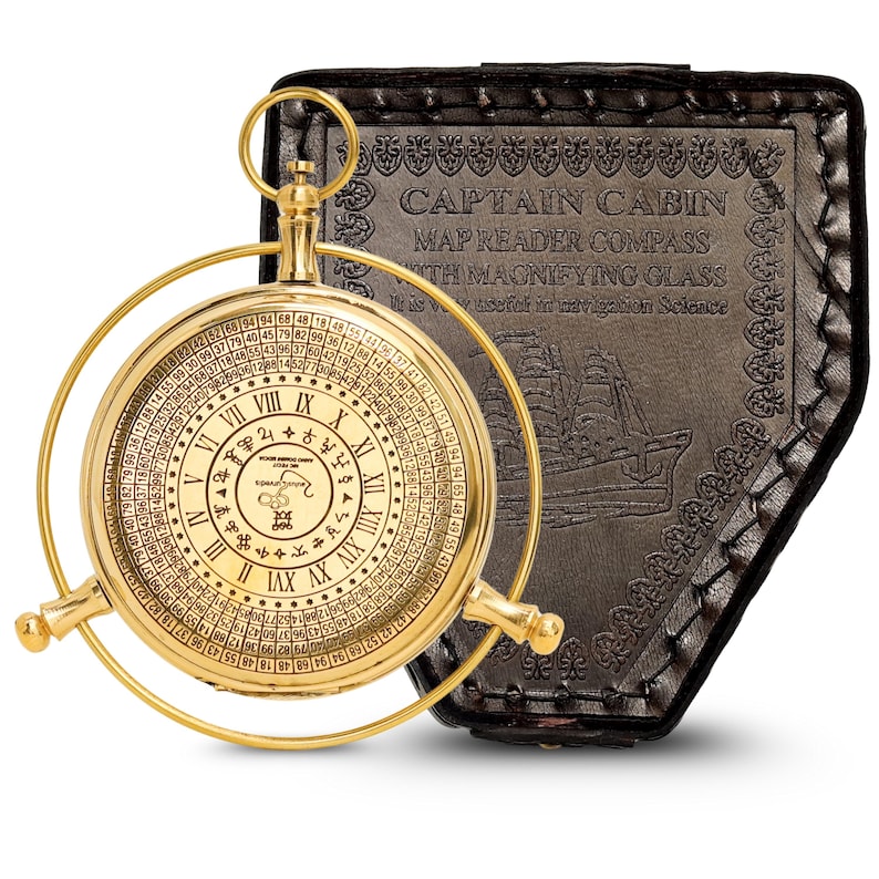 May include: A gold-colored Captain Cabin map reader compass with a magnifying glass. The compass features Roman numerals and a circular scale. It is housed in a black leather case with embossed text and a ship illustration.