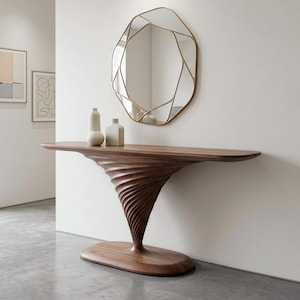 Puede incluir: Una mesa consola de madera oscura con una base en espiral tipo tornado y una superficie plana y alargada. Sobre la mesa hay dos jarrones de cerámica color hueso. Encima cuelga un espejo de pared irregular y facetado con un marco de metal dorado.