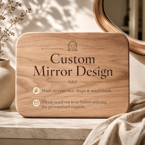 May include: A rectangular wooden sign with rounded corners, featuring the text "Custom Mirror Design" in a carved font. The sign also includes the text "Made to your size, shape & wood finish" and "Please reach out to us before ordering for personalized requests."
