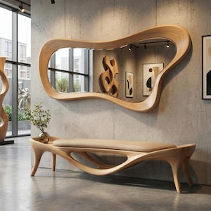 Puede incluir: Un espejo de madera moderno con una forma orgánica cuelga sobre un banco a juego. El banco tiene un diseño curvo con un cojín de color claro. La habitación presenta paredes de hormigón y una estética minimalista.