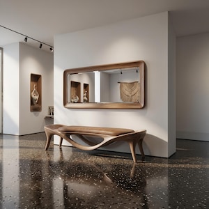 May include: A modern wooden bench with a unique, flowing design. The bench has a curved seat and legs, and is made of light brown wood. A large rectangular mirror with a wooden frame hangs on the wall above the bench.