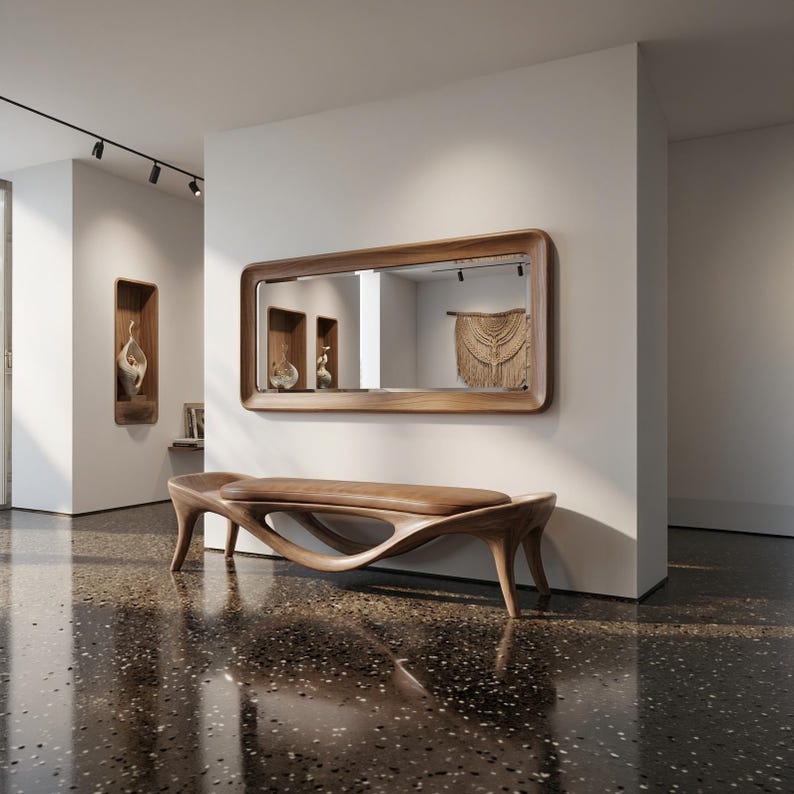 May include: A modern wooden bench with a unique, flowing design. The bench has a curved seat and legs, and is made of light brown wood. A large rectangular mirror with a wooden frame hangs on the wall above the bench.