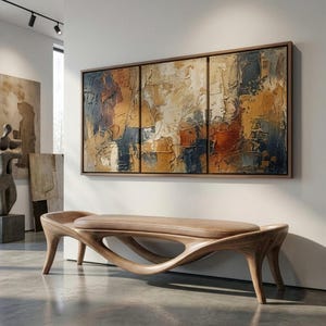 May include: A triptych abstract painting featuring thick, textured impasto brushstrokes in shades of ochre, deep blue, rust, and cream, framed in a thin wood border, positioned above a curved, light-toned wooden bench with a smooth, upholstered seat.