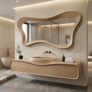 May include: A wall-mounted light wood vanity featuring a smooth, integrated basin and three drawers, paired with a large, organic-shaped mirror with a matching light wood frame. The set displays a consistent natural wood grain throughout the structure.