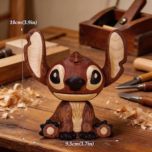 May include: A handcrafted wooden figurine of a cartoon character, featuring a dark brown body with lighter wood accents on the ears and belly. The figurine is approximately 3.9 inches (10cm) tall and 3.7 inches (9.5cm) wide. The character has large black eyes and a black nose.