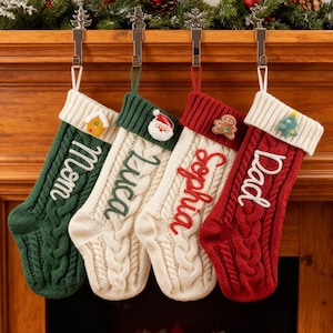 以下が含まれることがあります： 緑、クリーム、赤色のケーブルニットのクリスマスストッキングが4つ、マントルピースから吊り下げられています。各ストッキングには、Mom、Luca、Sophia、Dadの名前がパーソナライズされています。お祝いの装飾には、ジンジャーブレッドマン、サンタクロース、クリスマスツリーが含まれています。