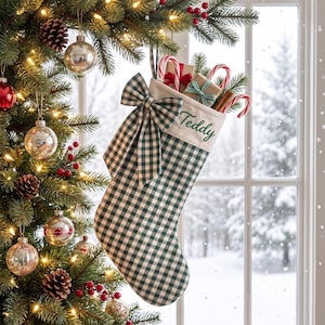 Peut inclure: Une chaussette de Noël à motif vichy vert foncé et blanc avec un grand nœud assorti. Le revers blanc est brodé du prénom Teddy en écriture verte. À l'intérieur de la chaussette se trouvent des cadeaux emballés et des sucres d'orge.