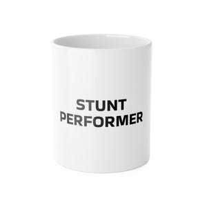 Op de afbeelding: Een witte keramische mok met de tekst STUNT PERFORMER in dikgedrukte zwarte hoofdletters op de voorzijde. De mok heeft een cilindrische vorm met een gladde afwerking en een brede opening aan de bovenkant, wat zorgt voor een strak ontwerp.