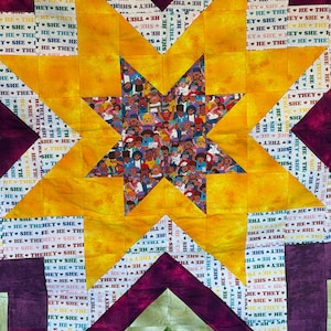 May include: A handmade quilt with a large yellow star design. The star's center features a crowd of diverse figures. The background includes geometric shapes and the repeated text "HE SHE THEY".