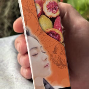 K&ouml;nnte beinhalten: Eine rechteckige Schachtel f&uuml;r GAC Anti-Aging Facial Serum mit orangefarbenem Hintergrund, Strichzeichnungen von Bl&auml;ttern, einem Foto von aufgeschnittenen Gac-Fr&uuml;chten und dem Profil einer Person mit geschlossenen Augen. Der Text GAC Anti-Aging Facial Serum ist aufgedruckt.