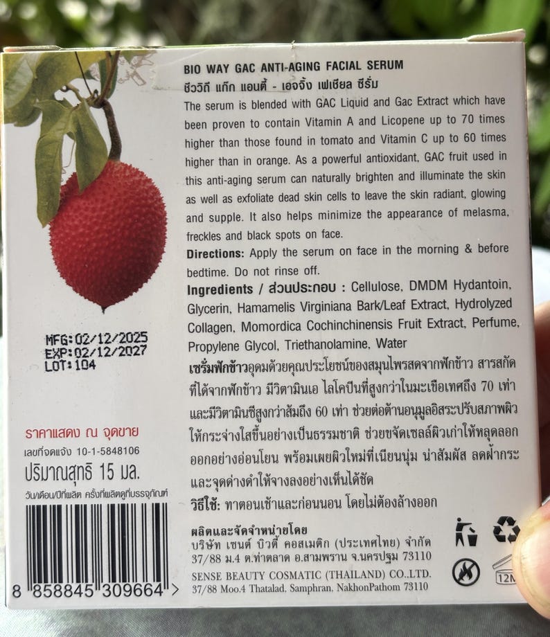K&ouml;nnte beinhalten: Eine quadratische Produktverpackung f&uuml;r Bio Way Gac Anti-Aging Gesichtsserum mit einer Abbildung einer roten Gac-Frucht. Die Verpackung enth&auml;lt englischen und thail&auml;ndischen Text mit Inhaltsstoffen, 15 ml Inhalt und Herstellungsdatum 02/12/2025.