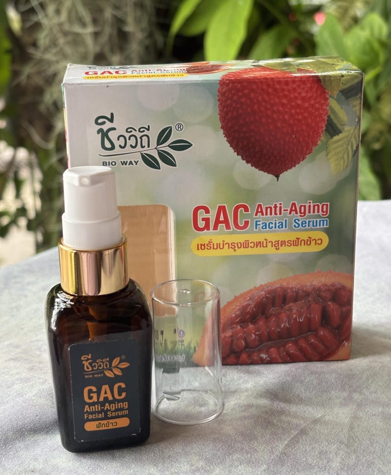 K&ouml;nnte beinhalten: Eine braune Glaspumpeflasche mit GAC Anti-Aging Gesichtsserum, schwarzem Etikett und wei&szlig;er Schrift, dazu eine transparente Kunststoffkappe und eine rechteckige Pappschachtel mit einer roten Gac-Frucht und dem Text GAC Anti-Aging Facial Serum.
