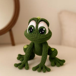 Può includere: Una rana verde all'uncinetto fatta a mano con grandi occhi espressivi. La rana ha un aspetto dettagliato e strutturato, con punti visibili e un design affascinante e stravagante. È un oggetto unico e fatto a mano.