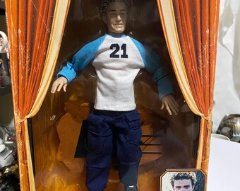 May include: An NSYNC collectible marionette doll in its original packaging. The doll wears a white and blue shirt with the number 21, navy blue pants, and black shoes. The packaging features the Living Toyz logo and a photo of Justin Timberlake.