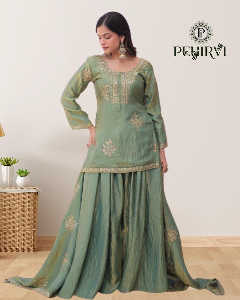 May include: A sage green, long-sleeved outfit with gold embroidery. The top has a scoop neckline and the skirt is floor-length. The outfit is from the brand PEHIRVI.