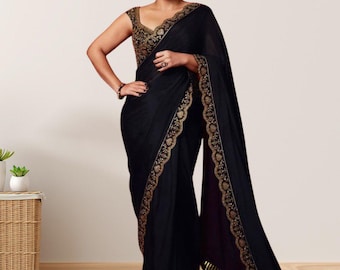 May include: A black saree with gold embroidery. The saree features intricate gold detailing along the borders and on the blouse. The image shows a woman wearing the saree, showcasing its elegant design and draping.