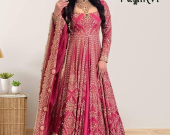 May include: A floor-length magenta anarkali gown featuring intricate gold embroidery, long sleeves, and a matching dupatta. The garment is adorned with detailed patterns and a wide border. The logo PEHIRVI is visible in the upper right corner.