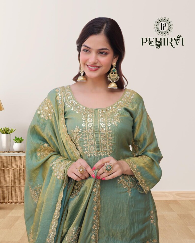 May include: A seafoam green ensemble featuring intricate gold embroidery. The outfit includes a long-sleeved tunic and a matching scarf. The design is embellished with gold accents and the brand name "PEHIRVI" is visible in the upper right corner.