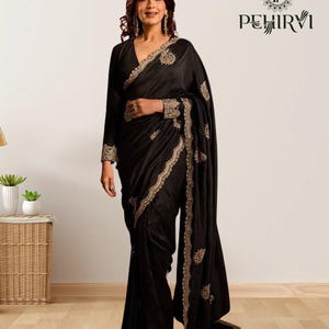 May include: A black sari with gold embroidery. The sari has a V-neck and long sleeves. Gold embroidery decorates the edges and sleeves. The sari is worn by a person.