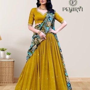 May include: Mustard yellow lehenga choli set with a matching dupatta. The set features intricate embroidery and a scalloped border with blue and white floral patterns. The top has a V-neck and short sleeves. The brand logo "PEHIRVI" is visible.