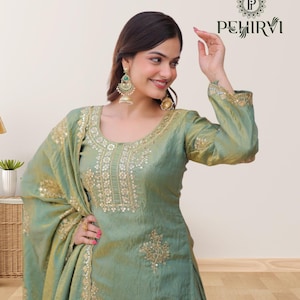 May include: A light green silk salwar kameez with gold embroidery and sequin embellishments. The outfit includes a matching dupatta and is adorned with intricate patterns. The image also shows a pair of gold earrings.