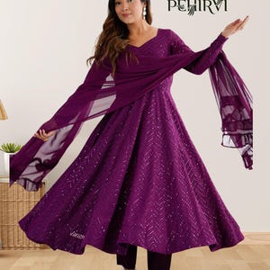 Puede incluir: Un vestido morado oscuro de manga larga con una falda fluida y una bufanda a juego. El vestido presenta un escote en V y está adornado con pequeños detalles brillantes. El conjunto se combina con pantalones morados oscuros. La marca "PEHIRVI" es visible.