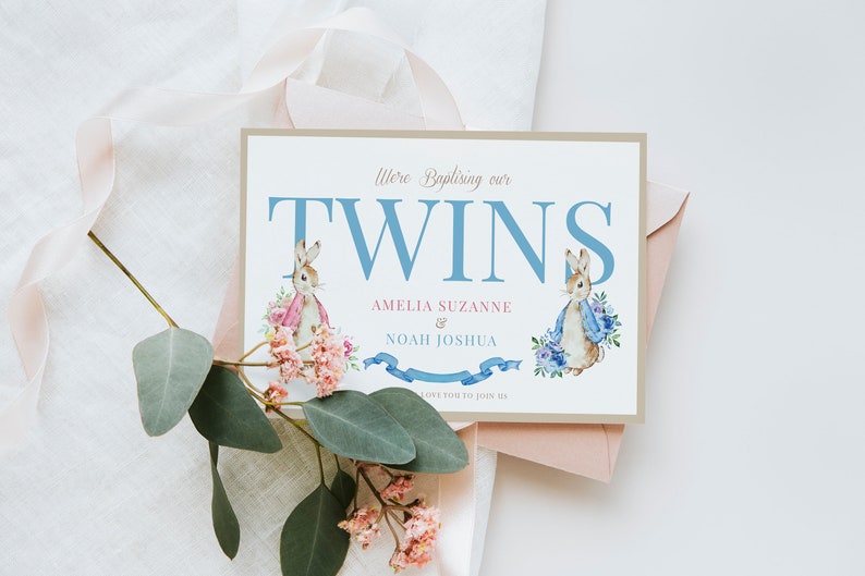 Puede incluir: Una tarjeta de invitaci&oacute;n de bautizo con una ilustraci&oacute;n de acuarela de dos conejos en azul y rosa. La tarjeta dice "We're Baptizing our Twins Amelia Suzanne & Noah Joshua. We'd love you to join us."
